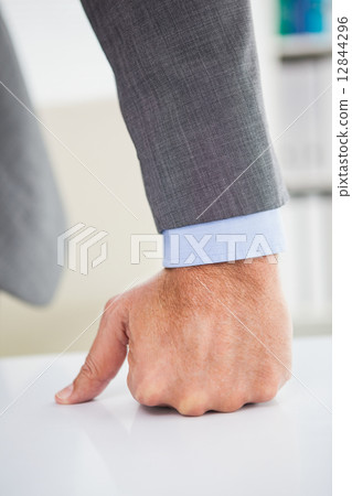 Businessmans fist clenched over desk 12844296