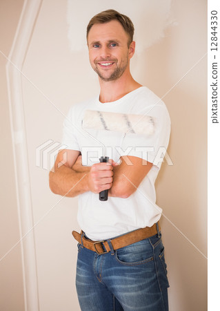 Smiling handyman posing while holding a paintbrush 12844330