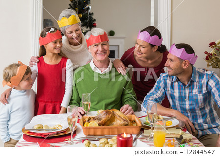 Happy extended family in party hat at dinner table Happy extended family in party hat at dinner table 12844547