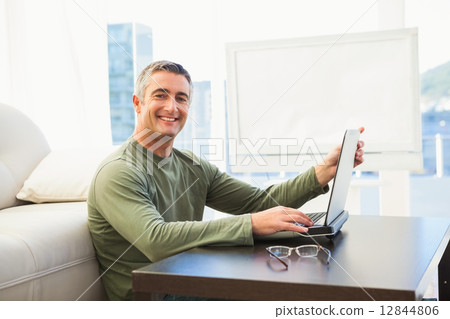 Smiling man using laptop with glasses on the table Smiling man using laptop with glasses on the table 12844806