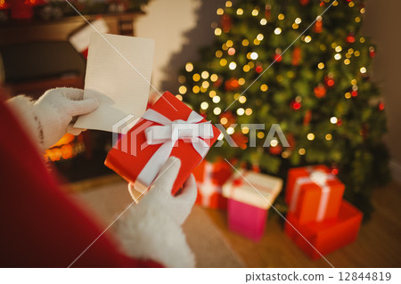 Santa claus holding paper and gift Santa claus holding paper and gift 12844819