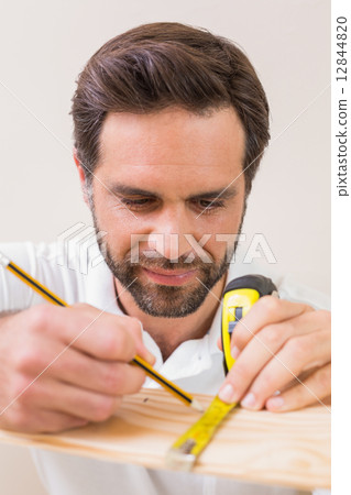 Casual man measuring plank of wood Casual man measuring plank of wood 12844820