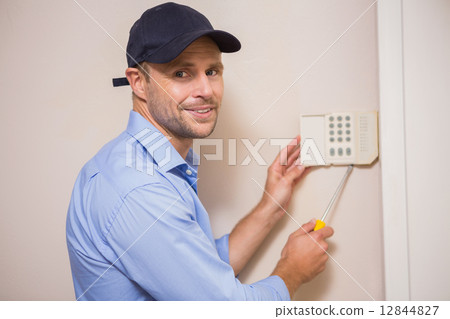 Handyman fixing an alarm system Handyman fixing an alarm system 12844827