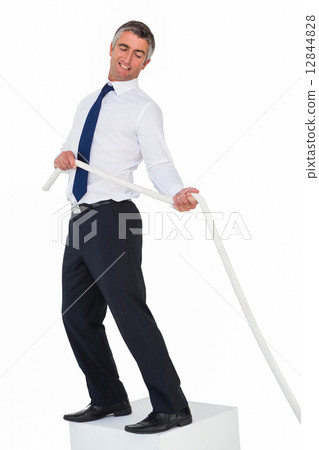 Smiling businessman standing on a cube and pulling rope Smiling businessman standing on a cube and pulling rope 12844828