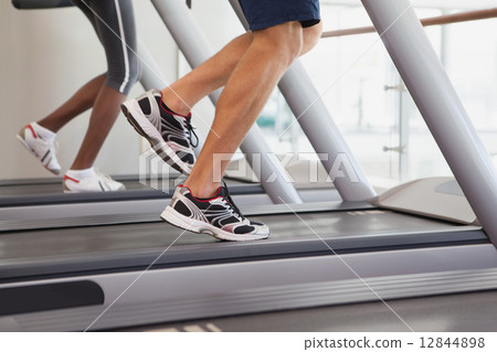 Fit people running on treadmills 12844898