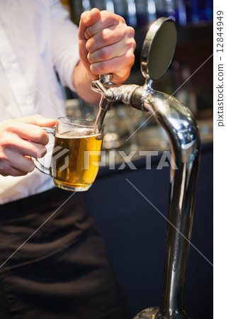 Handsome barkeeper pulling a pint of beer 12844949