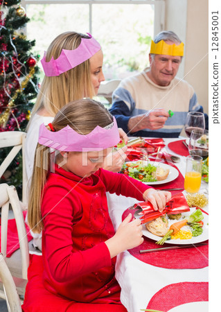 Little girl in party hat holding christmas crackers 12845001