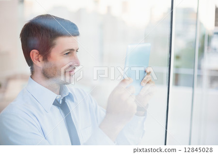 Businessman using tablet seen through window 12845028