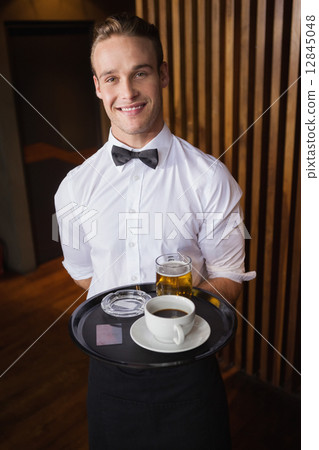 Smiling waiter holding tray with coffee cup and pint of beer 12845048