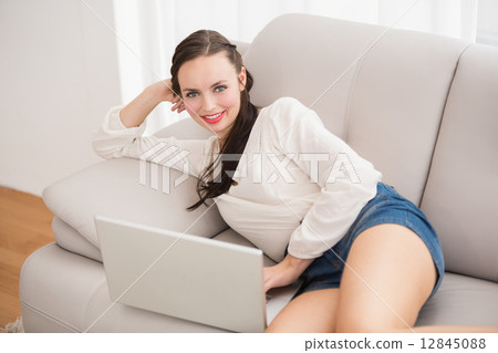 Pretty brunette using laptop on the couch 12845088