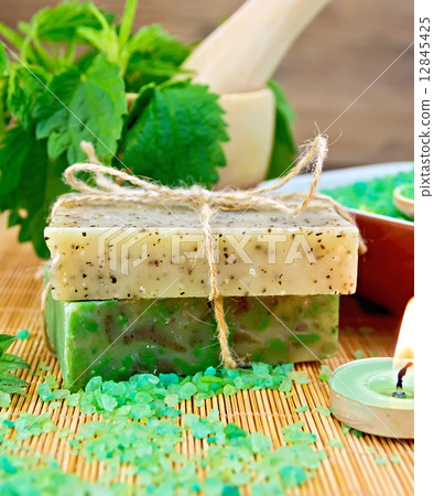 Soap homemade and candle with nettles in mortar on board Soap homemade and candle with nettles in mortar on board 12845425
