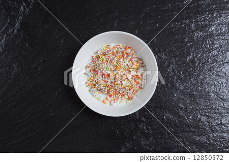 Sugar sprinkles in a bowl on a slate Sugar sprinkles in a bowl on a slate 12850572