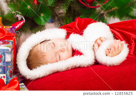 Baby in Santa costume sleeping at the Christmas tree with gifts Baby in Santa costume sleeping at the Christmas tree with gifts 12855625