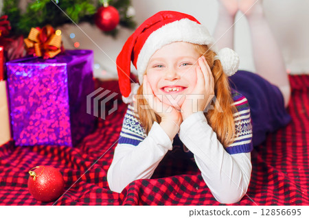 Little girl near the Christmas tree with gifts and toys 12856695