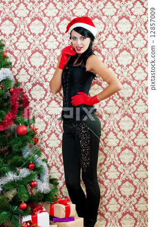 Beautiful girl in santa hat near a christmas tree with with Christmas toy 12857009