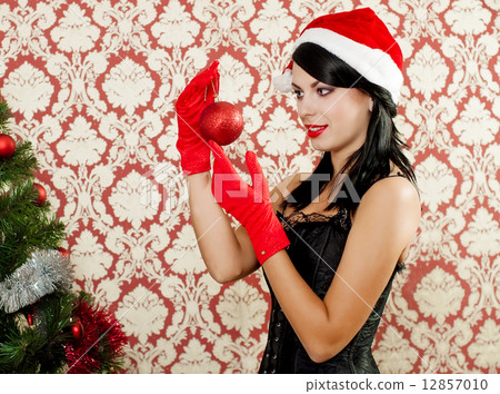 Beautiful girl in santa hat near a christmas tree with with Christmas toy 12857010