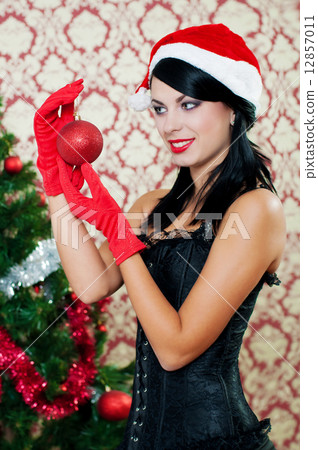 Beautiful girl in santa hat near a christmas tree with with Christmas toy 12857011