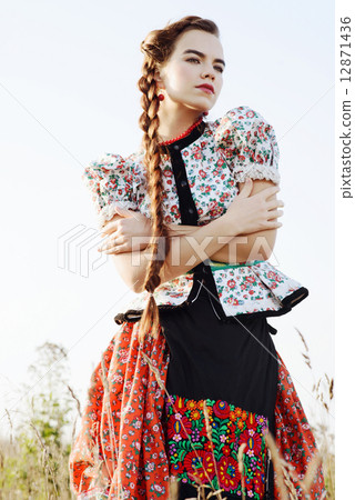Young peasant woman, dressed in Hungarian national costume, posing over nature background Young peasant woman, dressed in Hungarian national costume, posing over nature background 12871436