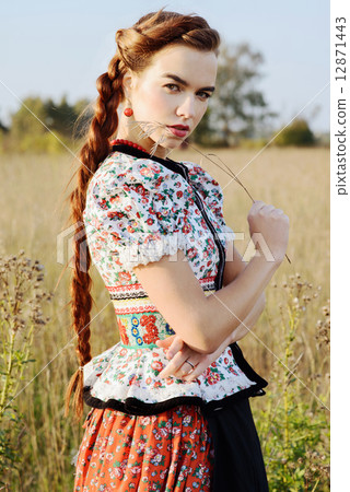 Young peasant woman, dressed in Hungarian national costume, posing over nature background 12871443