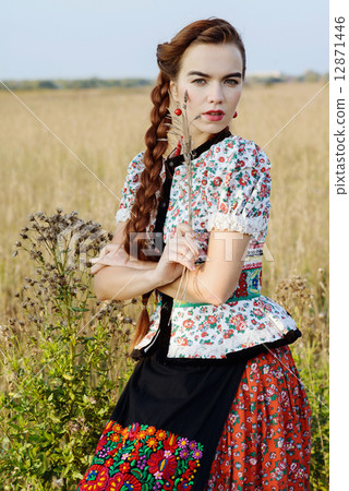 Young peasant woman, dressed in Hungarian national costume, posing over nature background 12871446