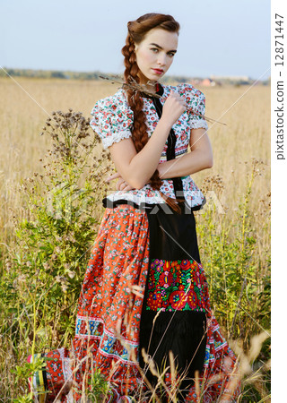 Young peasant woman, dressed in Hungarian national costume, posing over nature background 12871447