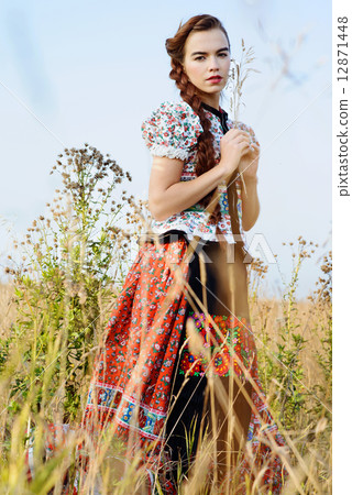 Young peasant woman, dressed in Hungarian national costume, posing over nature background 12871448