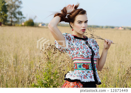 Young peasant woman, dressed in Hungarian national costume, posing over nature background 12871449