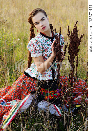 Young peasant woman, dressed in Hungarian national costume, posing over nature background 12871451