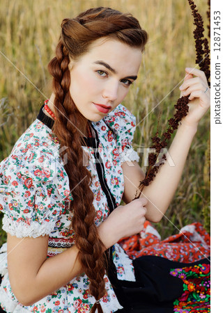 Young peasant woman, dressed in Hungarian national costume, posing over nature background 12871453