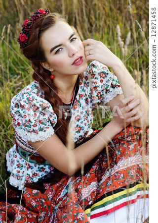 Young peasant woman, dressed in Hungarian national costume, posing over nature background 12871458