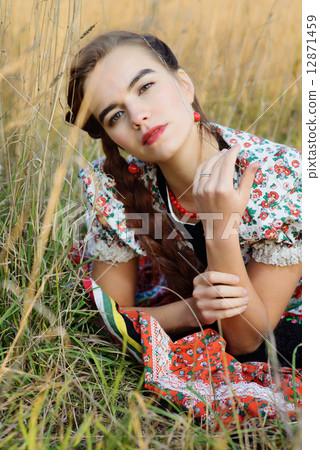 Young peasant woman, dressed in Hungarian national costume, posing over nature background 12871459