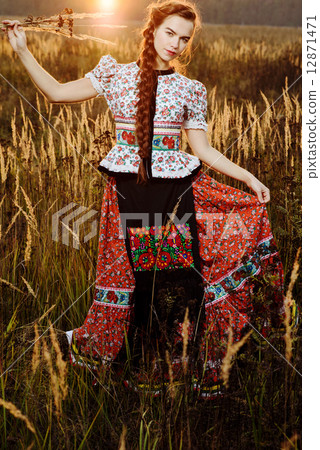 Young peasant woman, dressed in Hungarian national costume, posing over nature background Young peasant woman, dressed in Hungarian national costume, posing over nature background 12871471