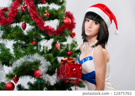 Beautiful girl in santa hat near a christmas tree with gifts 12875762