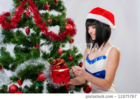 Beautiful girl in santa hat near a christmas tree with gifts 12875767