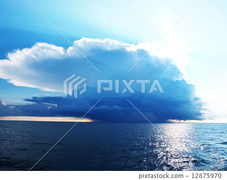 Bright blue sky with stormy clouds over a calm sea 12875970