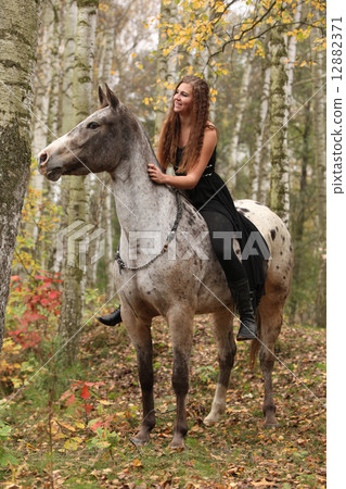 Young girl with appaloosa horse in autumn 12882371