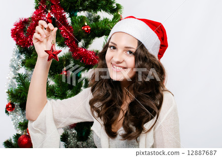 Beautiful girl in santa hat near a christmas tree with with Christmas toy 12887687