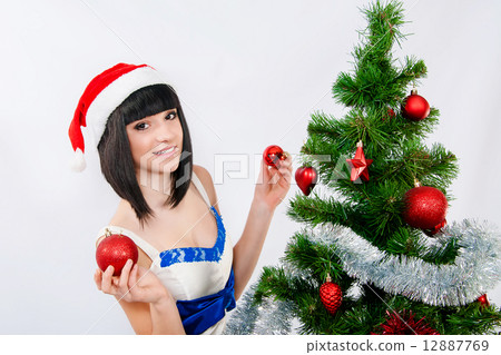 Beautiful girl in santa hat near a christmas tree with with Christmas toy 12887769