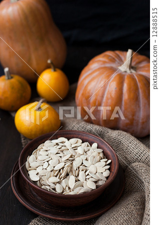 Pumpkins and a bowl with toasted pumpkin seeds, wooden spoon Pumpkins and a bowl with toasted pumpkin seeds, wooden spoon 12888515