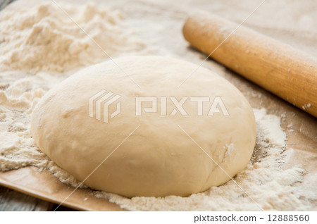 wooden rolling pin with freshly prepared dough for pizza wooden rolling pin with freshly prepared dough for pizza 12888560