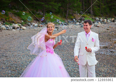 Bride and groom having fun with soap bubbles Bride and groom having fun with soap bubbles 12893861