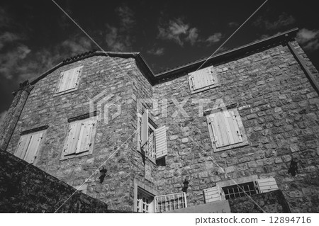 Monochrome photo of old stone house at sunny day 12894716