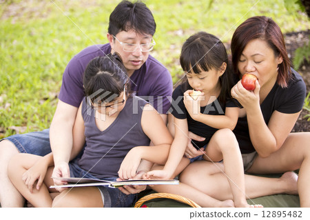 Young Asian family reading in park 12895482