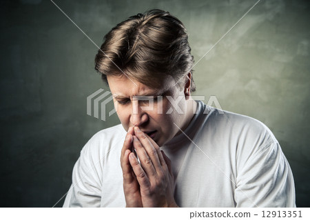 Young man praying on dark background 12913351