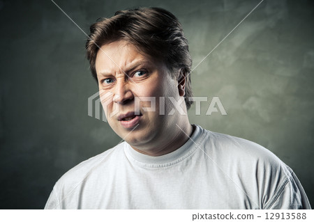 Man with disgusted expression over dark grey Man with disgusted expression over dark grey 12913588