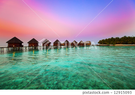 Island in ocean, overwater villas at the time sunset. 12915093