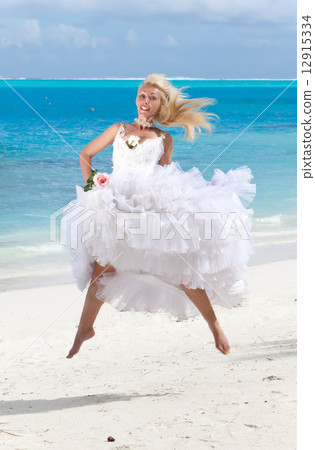 The young beautiful woman in a dress of the bride jumps at sea edge. The young beautiful woman in a dress of the bride jumps at sea edge. 12915334