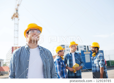 group of smiling builders in hardhats outdoors group of smiling builders in hardhats outdoors 12919785