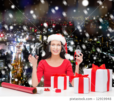 smiling woman in santa helper hat packing gifts smiling woman in santa helper hat packing gifts 12919948