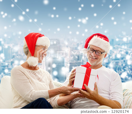 happy senior couple in santa hats with gift box happy senior couple in santa hats with gift box 12920174